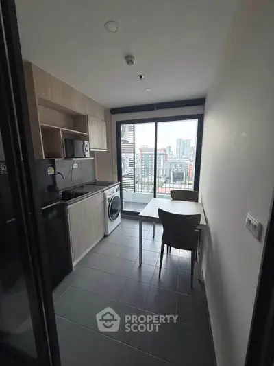 Modern kitchen with city view, featuring sleek cabinetry, washing machine, and dining area.