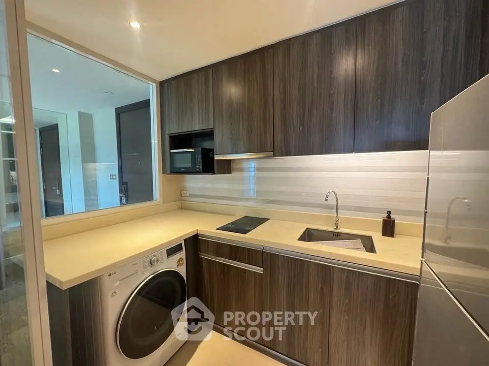 Modern kitchen with sleek cabinetry, built-in appliances, and washing machine in a compact layout.