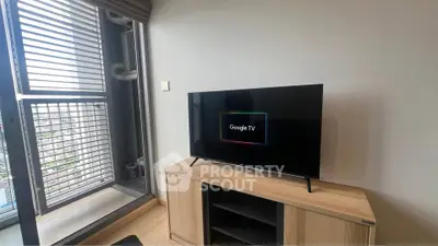 Modern living room with sleek TV and balcony view in urban apartment.