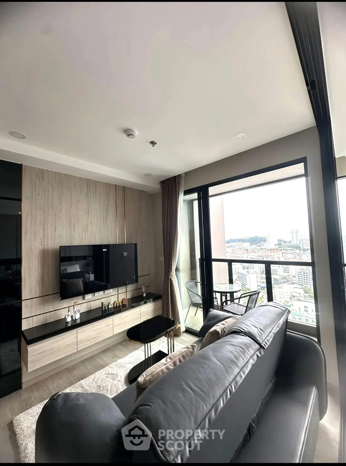 Modern living room with sleek design and stunning city view from balcony.