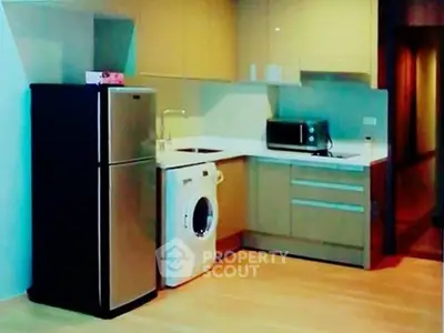 Modern kitchen with sleek appliances including fridge and washing machine, ideal for urban living.