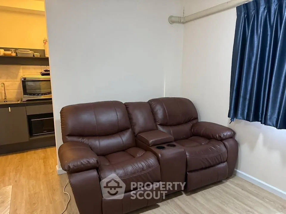 Cozy living room with leather recliner sofa and modern kitchen view