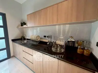 Modern kitchen with sleek cabinetry and black countertops, featuring a minimalist design and ample storage space.