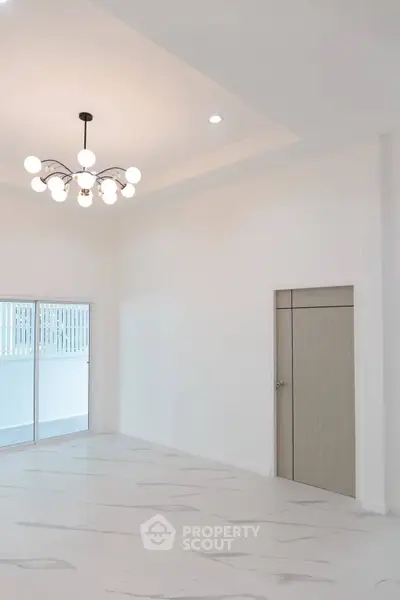 Spacious modern living room with elegant chandelier and sliding glass doors.