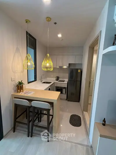 Modern kitchen with sleek design, featuring pendant lights and breakfast bar seating.