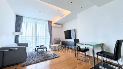 Modern living room with sleek furniture and large windows offering city views.