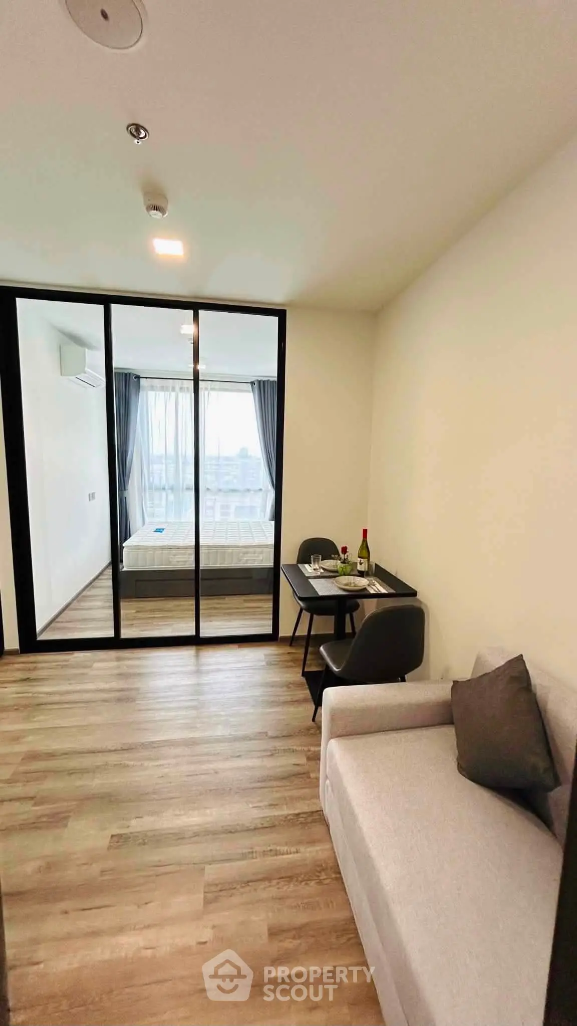 Modern apartment interior with glass partition, cozy living area, and stylish bedroom view.