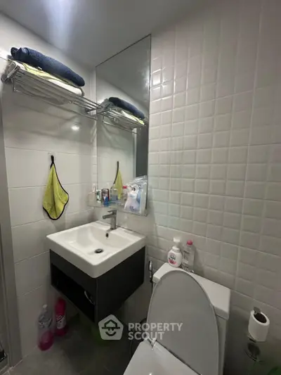 Modern bathroom with sleek sink and tiled walls, featuring practical storage solutions.