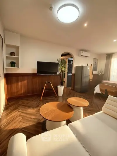 Stylish living room with modern decor and natural light, featuring a cozy seating area and sleek wooden flooring.