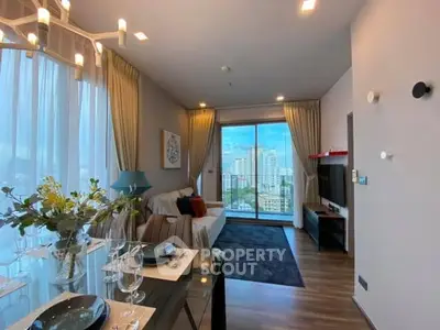 Modern living room with city view, elegant decor, and natural light in a high-rise apartment.