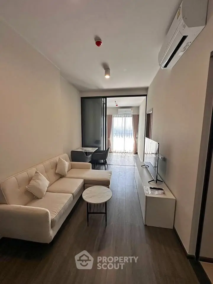 Modern living room with sleek furniture and natural light, featuring a cozy sofa and flat-screen TV.