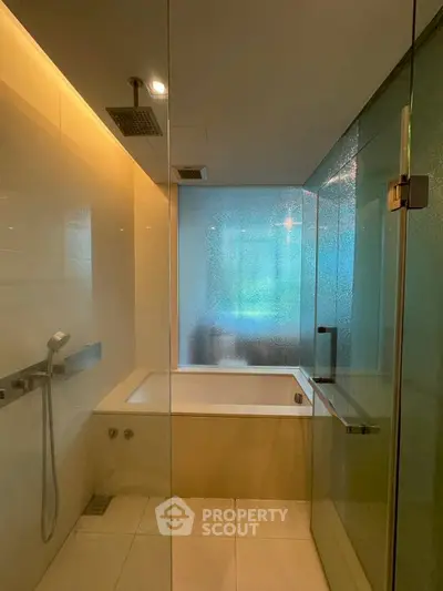 Luxurious modern bathroom with glass shower and bathtub in upscale apartment.