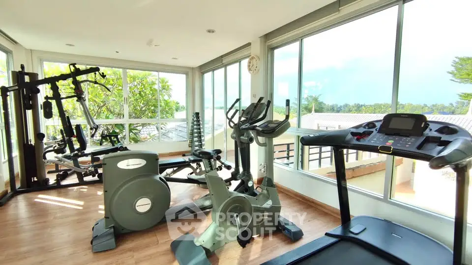 Bright home gym with modern exercise equipment and large windows offering scenic views.