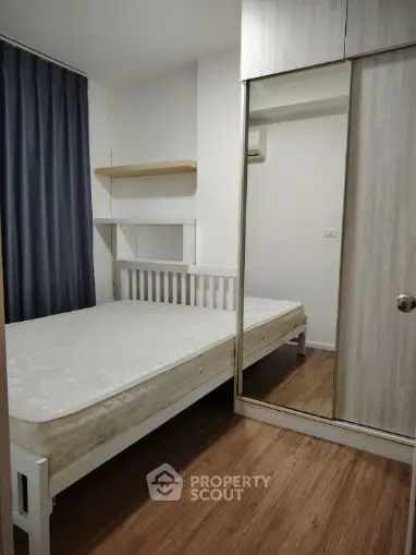 Cozy bedroom with wooden flooring and mirrored wardrobe in modern apartment.