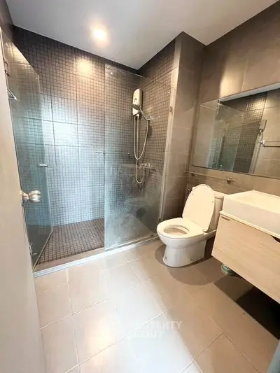 Modern bathroom with glass shower and sleek fixtures in contemporary apartment.