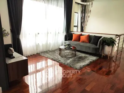 Elegant living room with polished wooden floors, stylish sofa, and large windows with flowing curtains.