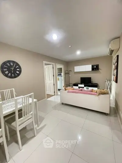 Modern living room with white furniture and wall clock, open layout design.