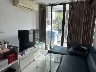 Modern living room with sleek furniture and large TV, featuring a balcony view.