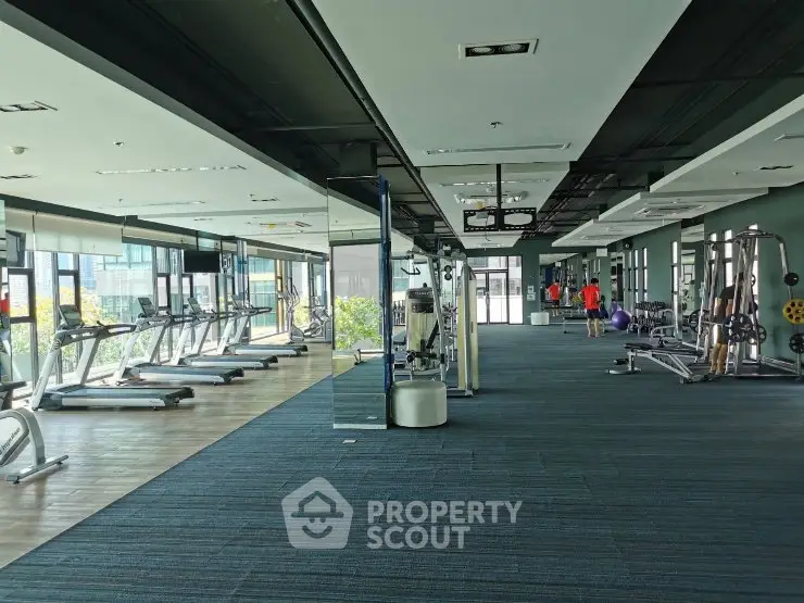 Spacious modern gym with state-of-the-art equipment and large windows offering natural light.