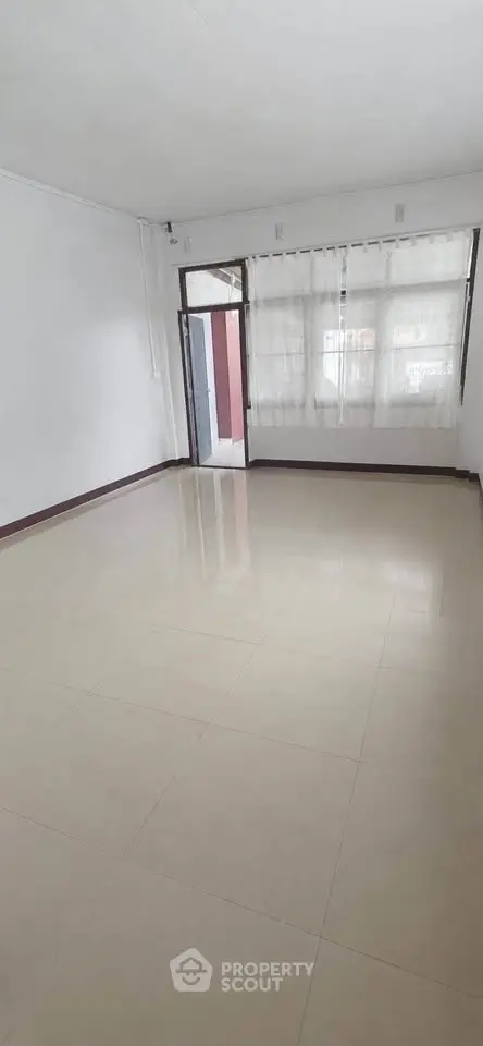 Spacious empty room with large window and tiled floor, perfect for customization.