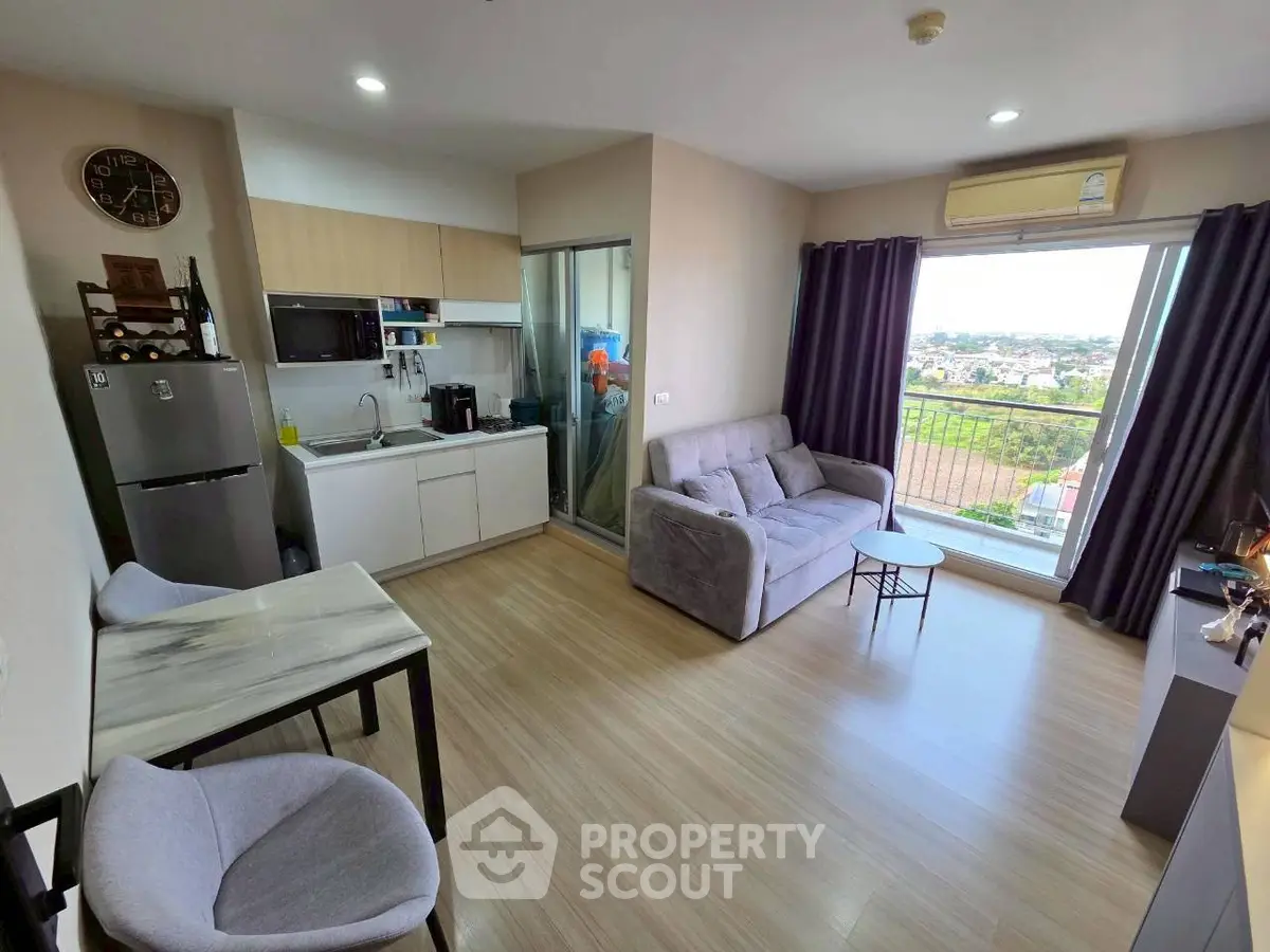 Modern living room with open kitchen and scenic view from balcony in high-rise apartment.
