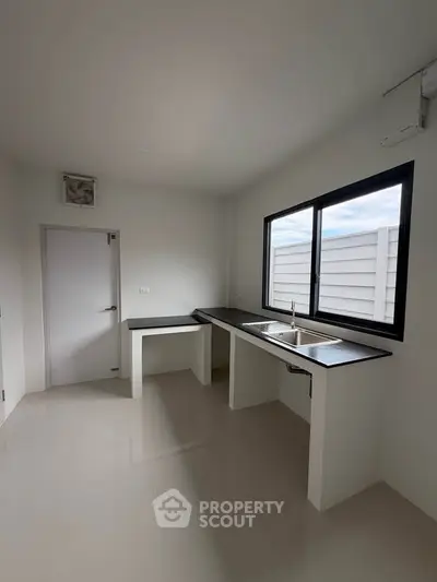 Modern minimalist kitchen with sleek countertops and large window for natural light.