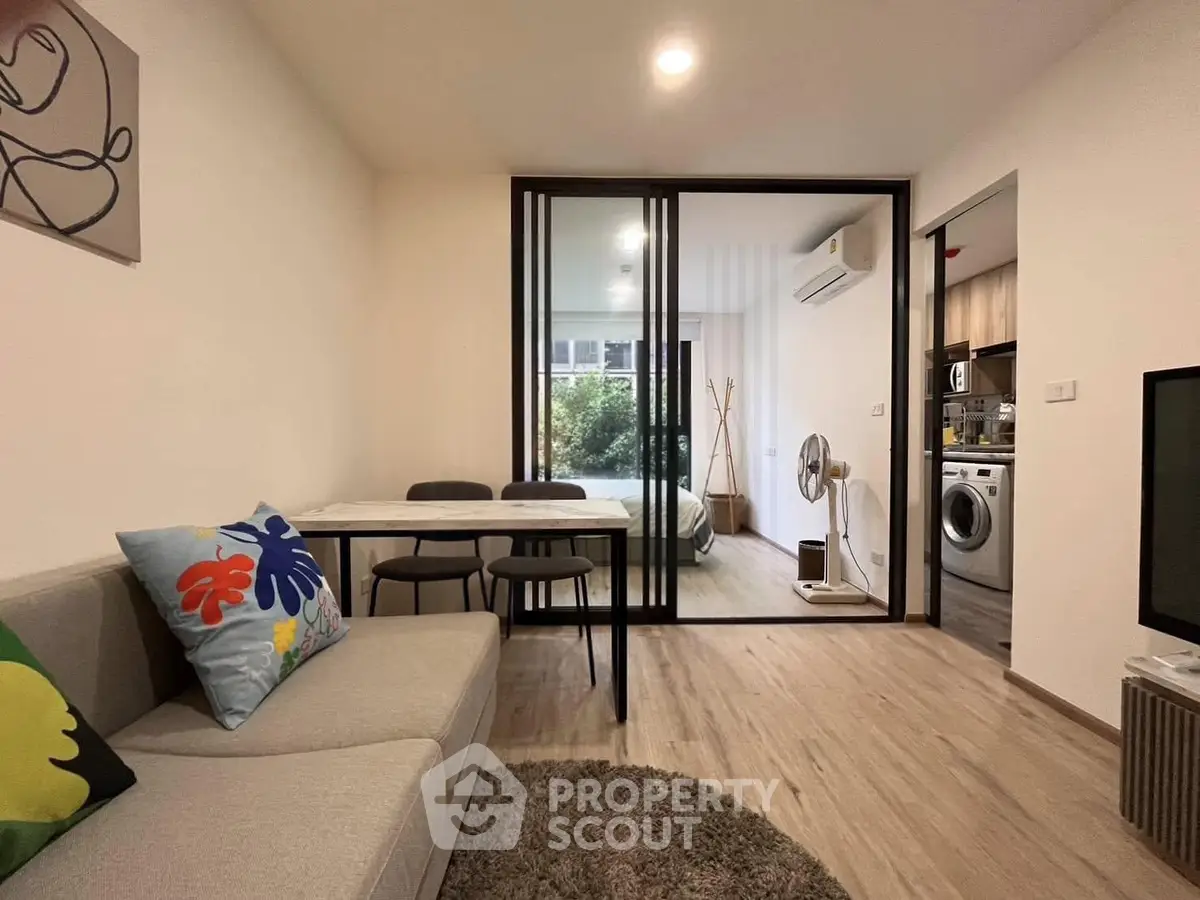 Modern living room with stylish decor and open layout leading to bedroom and kitchen.