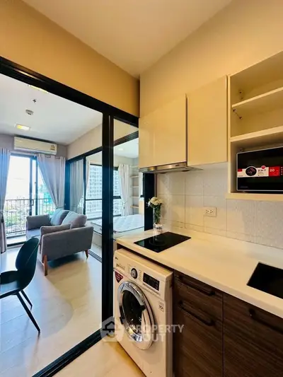 Modern apartment with open kitchen and cozy living area, featuring a washing machine and stylish decor.