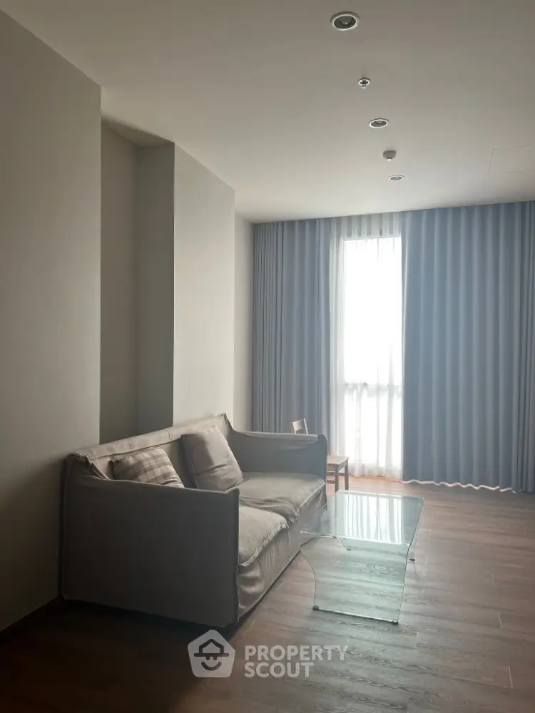 Modern living room with cozy sofa and glass coffee table, featuring floor-to-ceiling curtains for elegant ambiance.