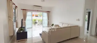 Spacious living room with modern sofa and large windows opening to a balcony.