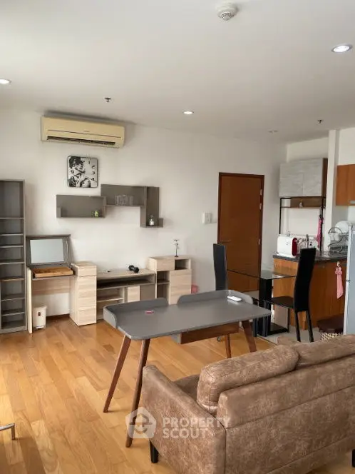 Modern living room with wooden flooring and open kitchen layout in cozy apartment.