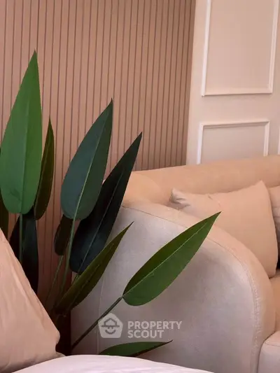 Elegant living room with modern beige sofa and lush green plant, creating a cozy and stylish ambiance.