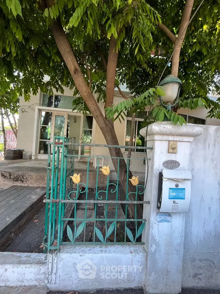 Charming property entrance with lush greenery and decorative gate, perfect for a serene urban retreat.