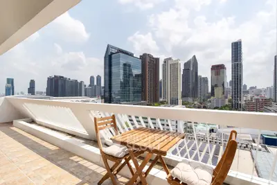 Stunning cityscape view from a spacious balcony with modern outdoor seating, perfect for relaxation.