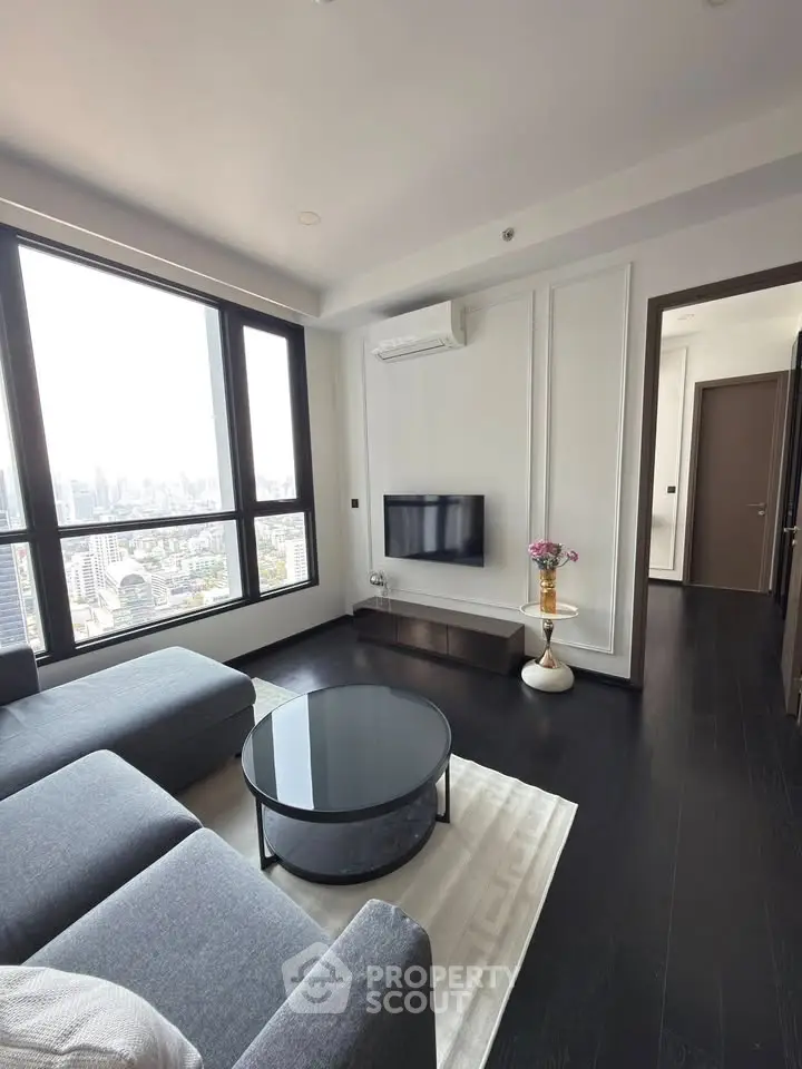 Modern living room with panoramic city view, sleek furniture, and elegant decor in a high-rise apartment.