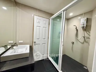 Modern bathroom with sleek shower and stylish sink in contemporary apartment.