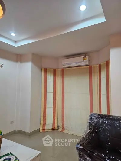 Cozy living room with modern lighting and air conditioning, featuring elegant curtains and a comfortable seating area.