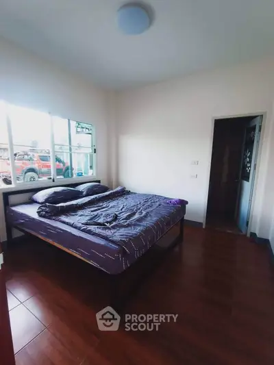 Cozy bedroom with natural light and wooden flooring, perfect for relaxation.