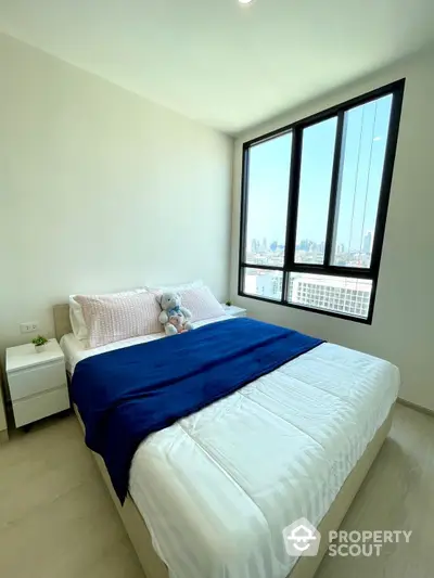 Bright and airy bedroom with large windows offering a stunning city view, complemented by a cozy bed and modern minimalist decor.