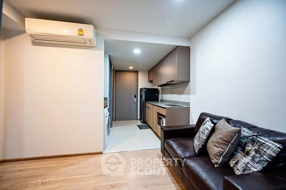Modern living room with sleek kitchen and cozy leather sofa in open layout apartment.