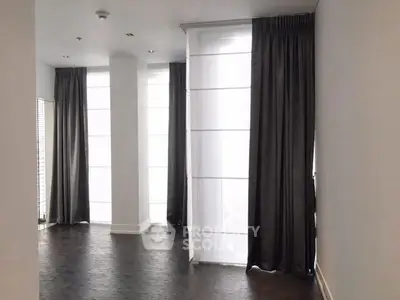 Spacious modern room with floor-to-ceiling windows and elegant dark curtains.