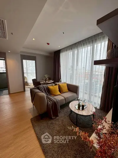 Modern living room with cozy sofa and large windows offering city views.