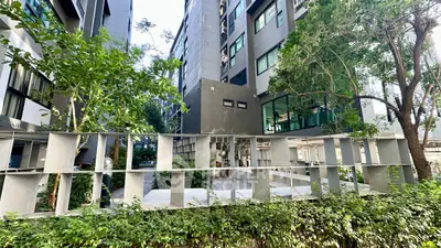 Modern apartment building exterior with lush greenery and unique architectural design.