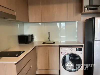 Modern kitchen with sleek cabinetry, washing machine, and glass backsplash