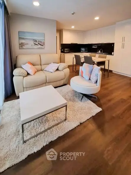 Modern open-layout living room with cozy seating and stylish kitchen area, perfect for contemporary living.