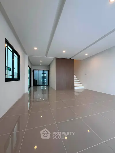 Spacious modern living room with sleek tile flooring and elegant staircase