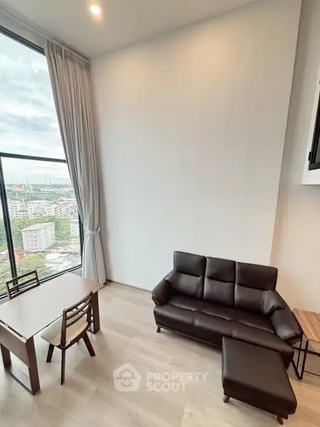 Modern living room with city view, featuring sleek furniture and large windows for natural light.