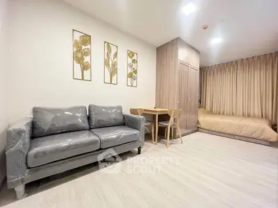 Modern studio apartment with stylish decor and cozy furnishings, featuring a sleek sofa and elegant wall art.