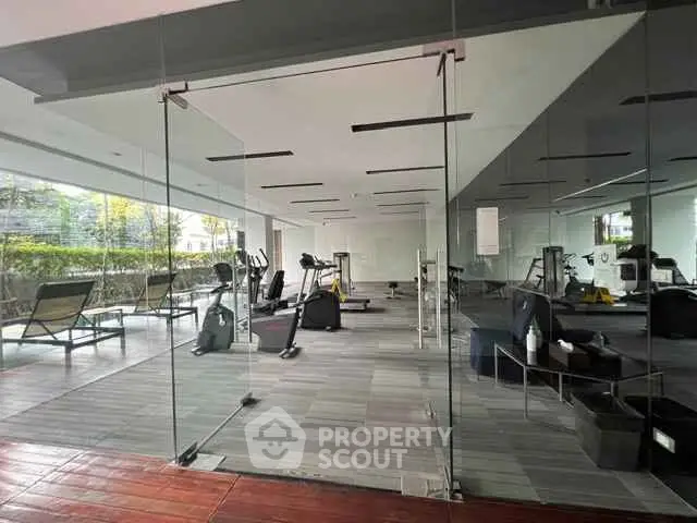 Modern gym with glass walls and fitness equipment in a luxury residential building.