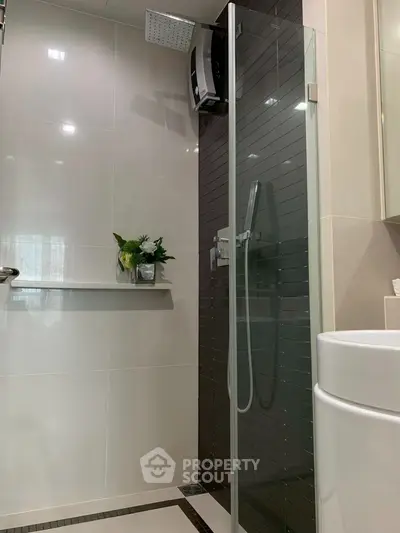 Modern bathroom with sleek glass shower and elegant black tile accent wall.